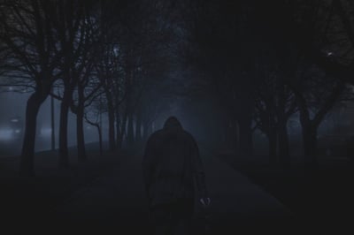 Man walking between trees at night.