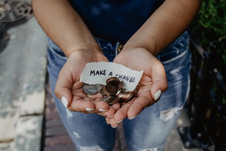 A person holding change in their hands with a sign "make a change"